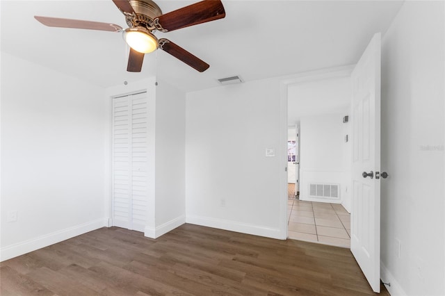 unfurnished bedroom with ceiling fan, wood-type flooring, and a closet