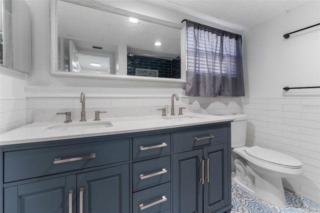 bathroom featuring tile patterned floors, a textured ceiling, toilet, vanity, and tile walls