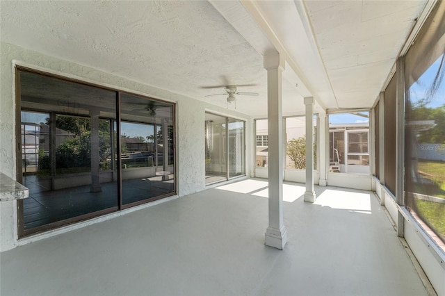 unfurnished sunroom with decorative columns and ceiling fan