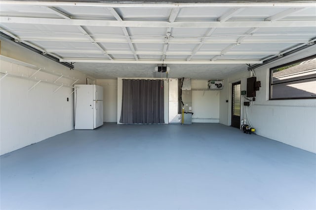 garage with electric panel, white fridge, and a garage door opener