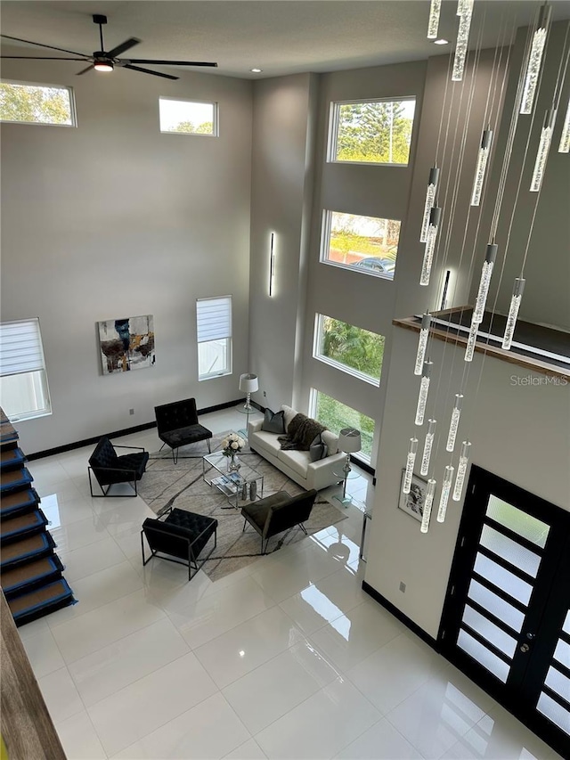 living room featuring ceiling fan, a high ceiling, and light tile patterned flooring