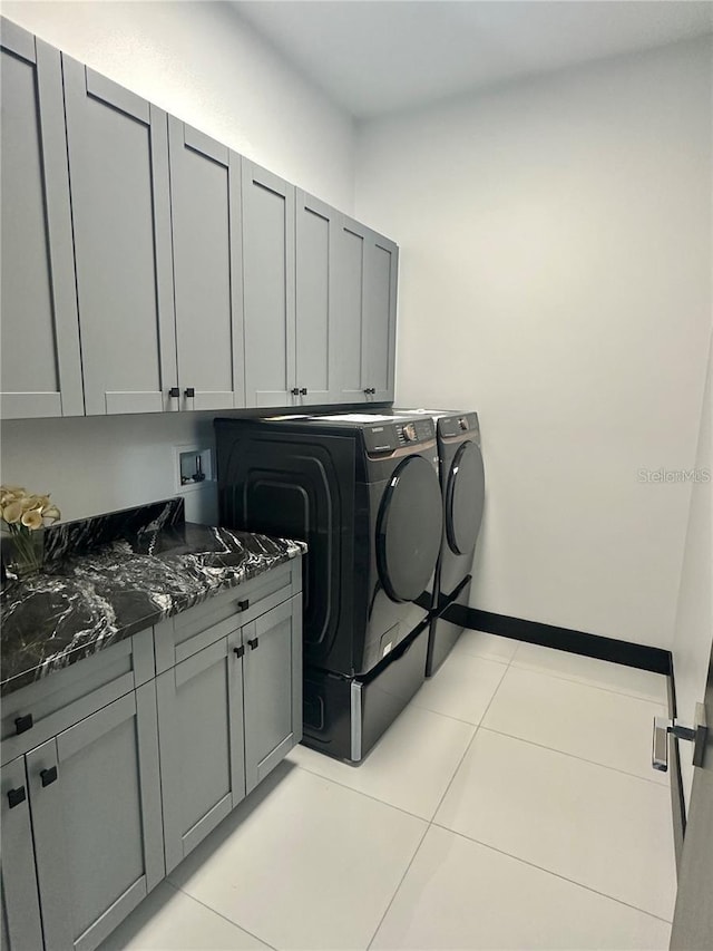 laundry room with light tile patterned floors, cabinets, and washer and clothes dryer