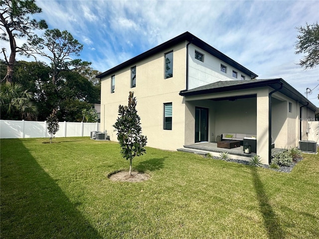 rear view of property with a patio area, a yard, and central AC