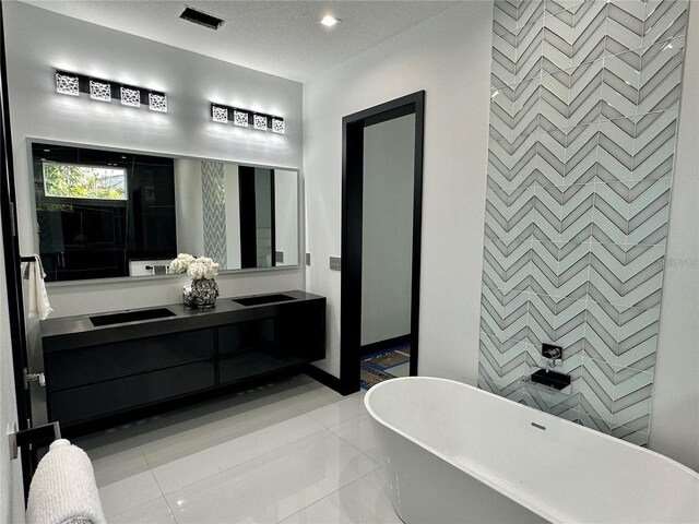 bathroom with vanity, a bathtub, a textured ceiling, and tile patterned flooring