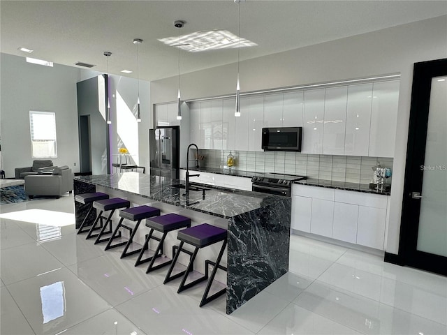 kitchen featuring white cabinetry, a large island, sink, decorative light fixtures, and black electric range