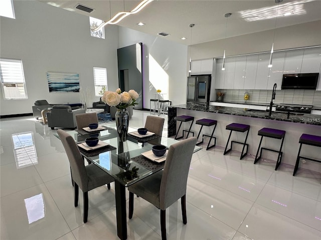 dining area with a towering ceiling and light tile patterned floors