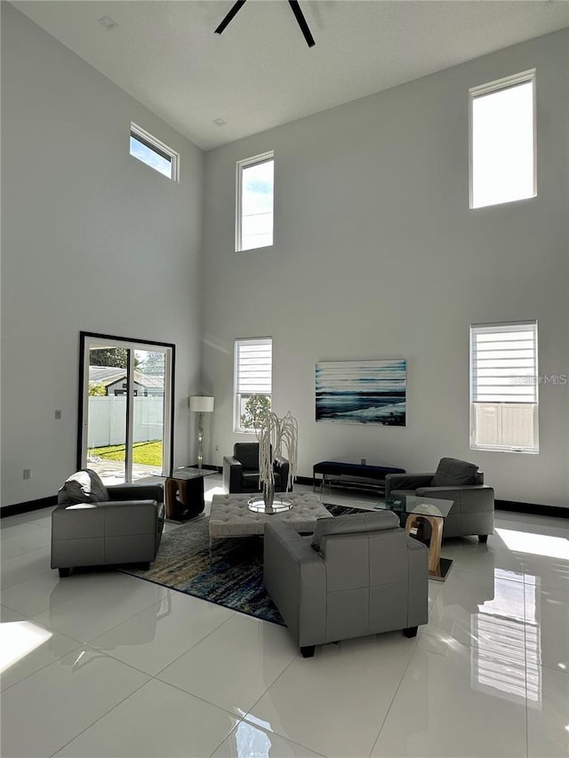 living room with ceiling fan, a high ceiling, and light tile patterned floors