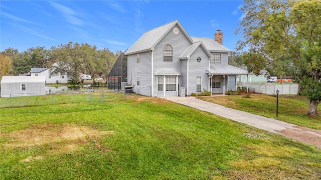 rear view of property with a lawn and glass enclosure