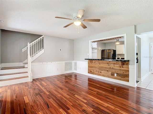 unfurnished living room featuring ceiling fan, light hardwood / wood-style flooring, and a textured ceiling