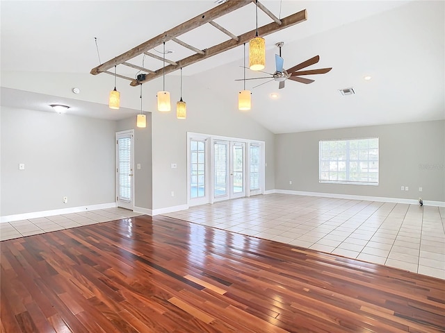 empty room featuring hardwood / wood-style floors, ceiling fan, beam ceiling, and high vaulted ceiling