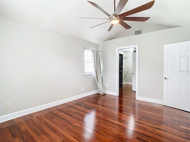 unfurnished bedroom featuring lofted ceiling, ceiling fan, dark wood-type flooring, and a spacious closet