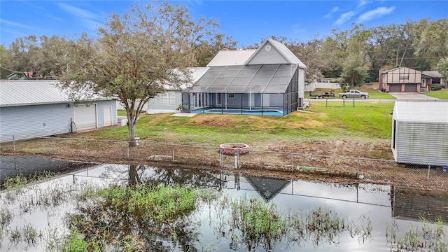 back of house featuring a lanai, a yard, and a water view