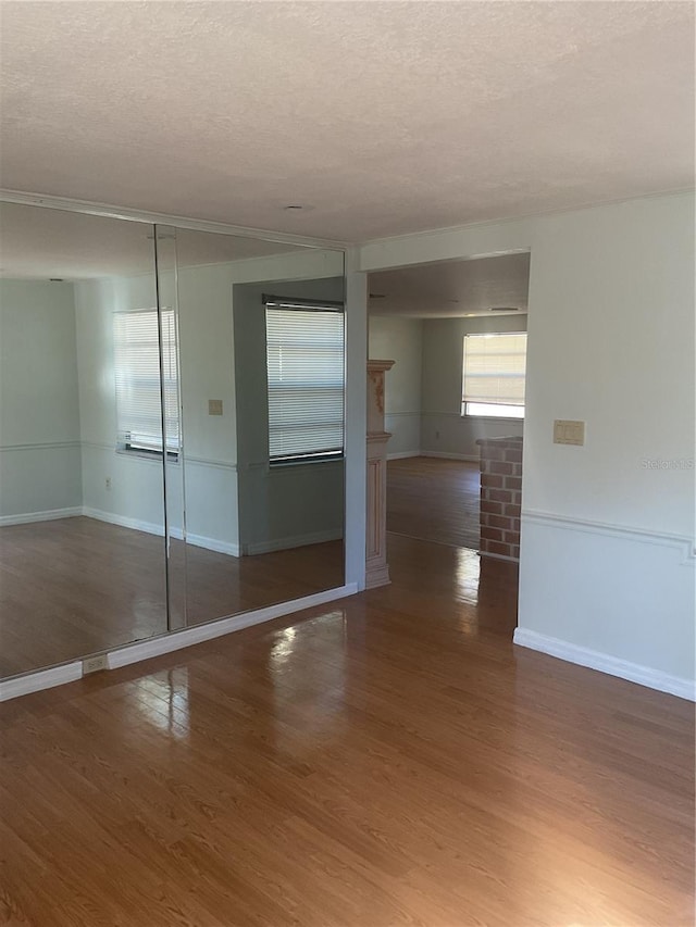 empty room with a textured ceiling and dark hardwood / wood-style floors