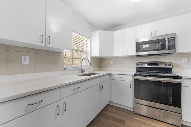 kitchen with appliances with stainless steel finishes, sink, dark wood-type flooring, and white cabinets