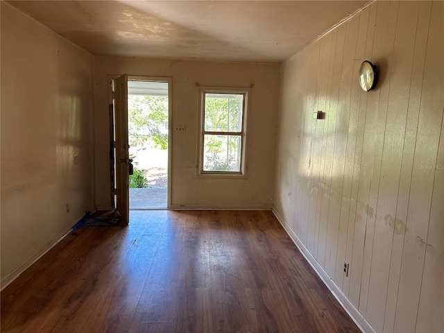 unfurnished room with wooden walls and dark hardwood / wood-style floors