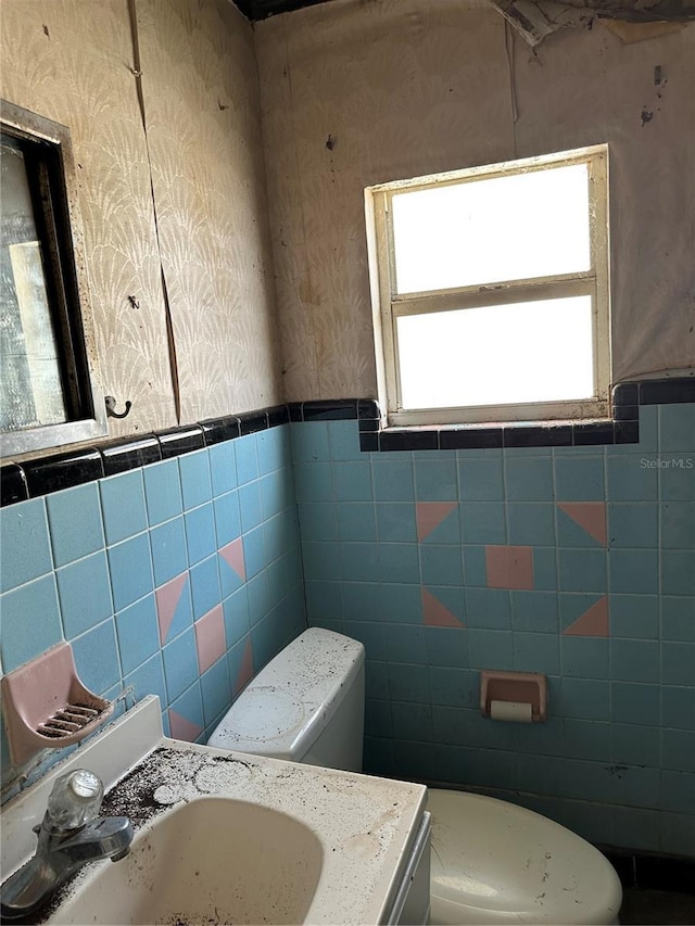 bathroom with vanity, toilet, and tile walls