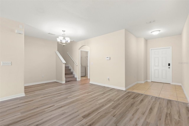 interior space with light hardwood / wood-style floors, washer / clothes dryer, and a notable chandelier