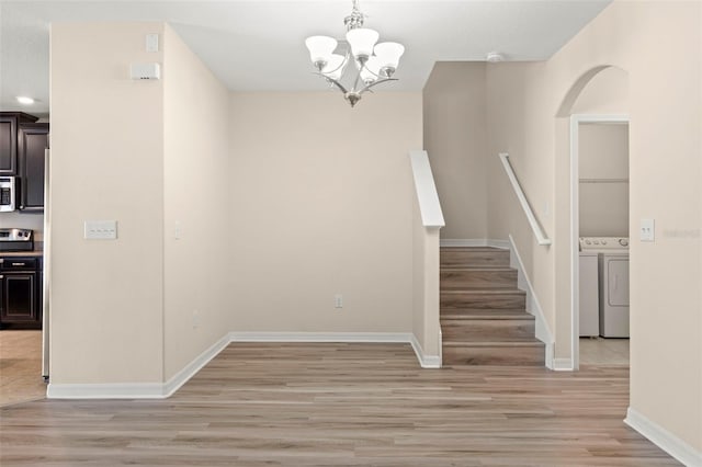 staircase with separate washer and dryer, an inviting chandelier, and hardwood / wood-style flooring