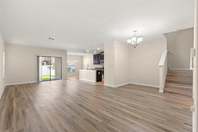 unfurnished living room featuring light wood-type flooring and an inviting chandelier