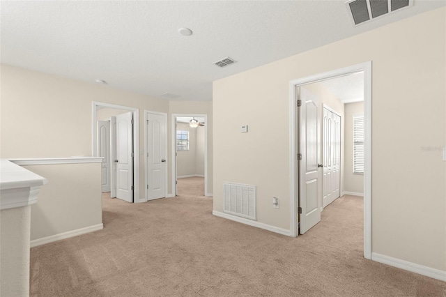 unfurnished room with light colored carpet and a textured ceiling