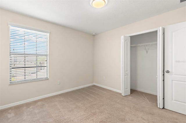 unfurnished bedroom featuring light colored carpet and a closet