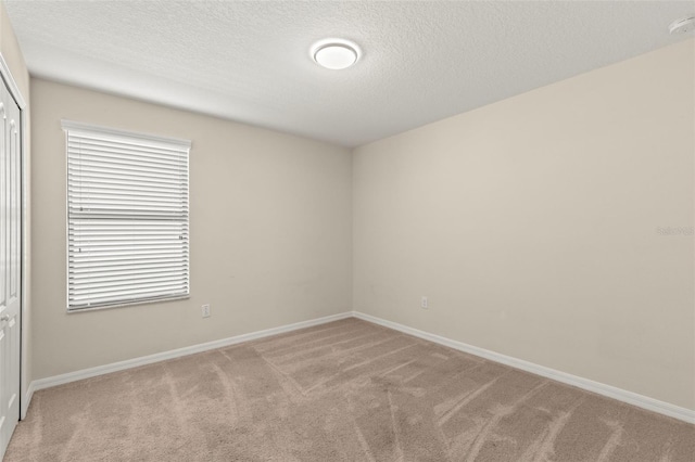 spare room with light colored carpet and a textured ceiling