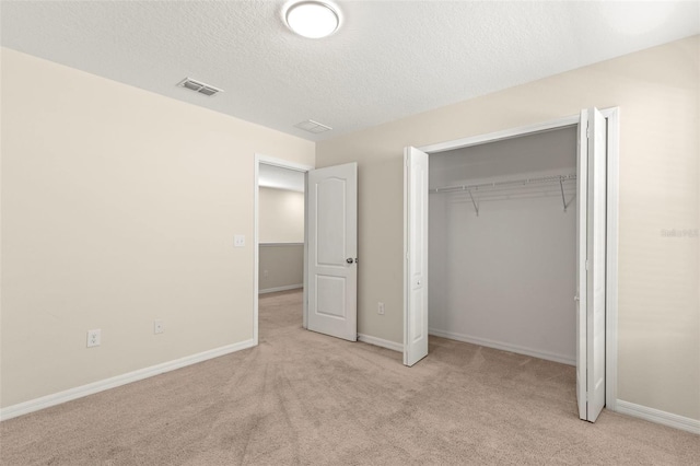 unfurnished bedroom with light carpet, a closet, and a textured ceiling