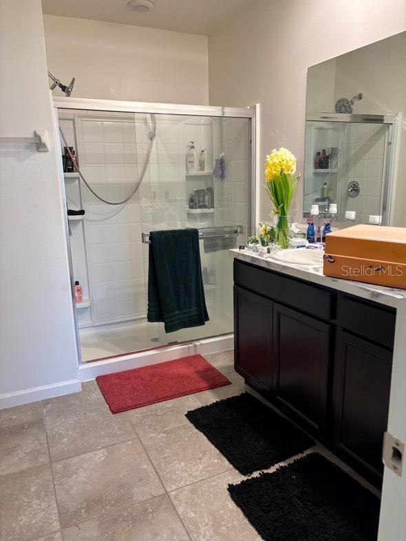 bathroom with tile patterned flooring, vanity, and an enclosed shower