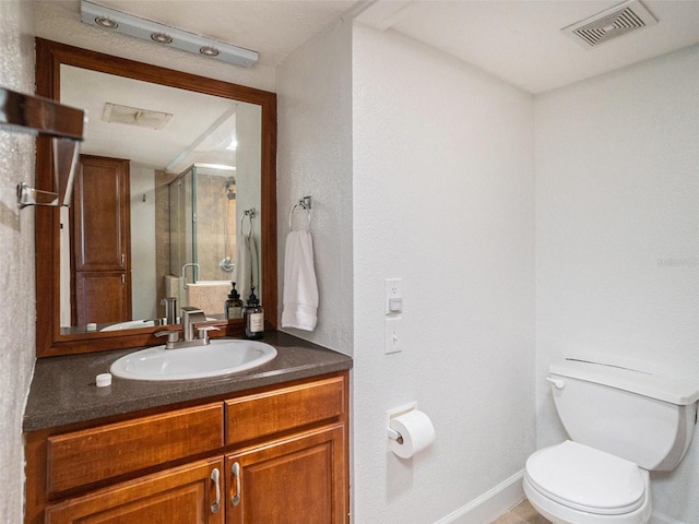 bathroom with a shower with door, vanity, and toilet