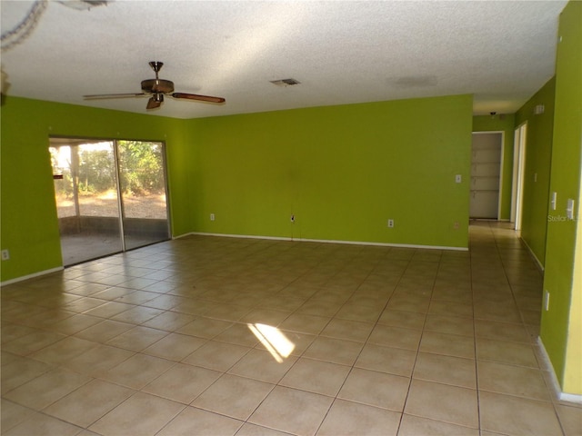 unfurnished room with ceiling fan, light tile patterned floors, and a textured ceiling