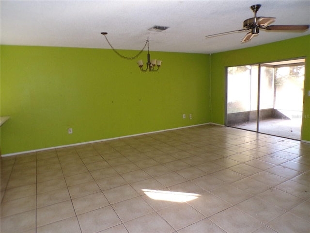 tiled spare room featuring ceiling fan with notable chandelier