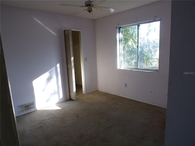 carpeted spare room with ceiling fan