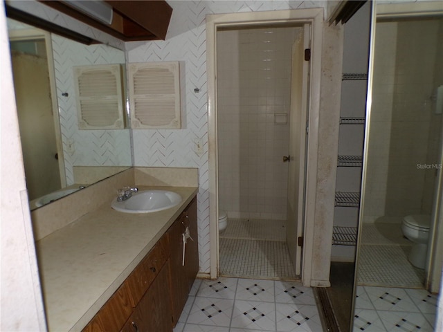 bathroom with tiled shower, vanity, and toilet