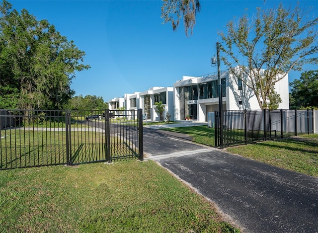 view of gate with a fenced front yard, a residential view, and a yard