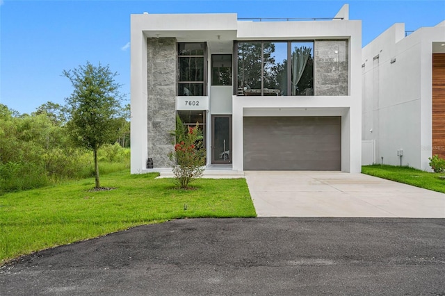 contemporary house with concrete driveway, an attached garage, a front yard, and stucco siding