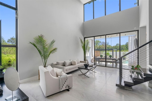 tiled living area featuring stairway, a high ceiling, and baseboards