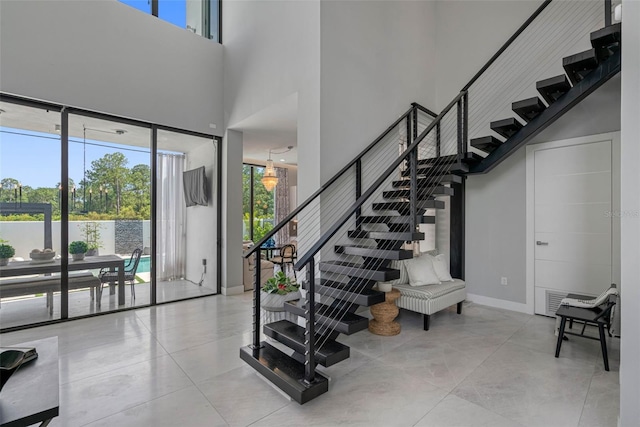 stairway with a wealth of natural light, a high ceiling, and baseboards