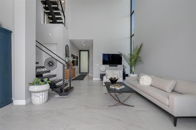 living room featuring stairway, baseboards, a high ceiling, and concrete flooring