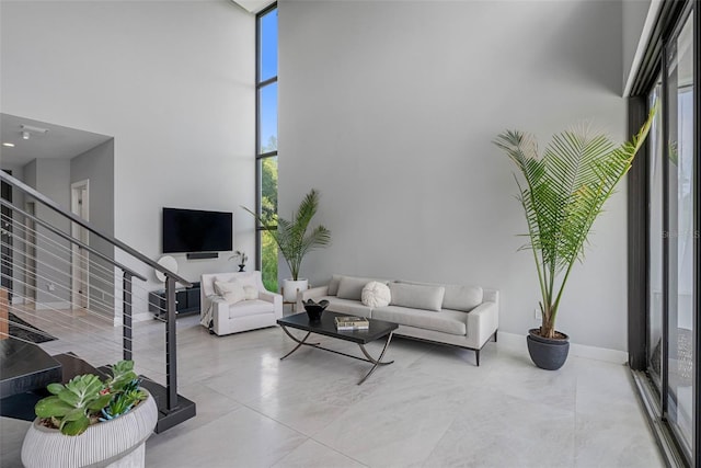 living room with stairs, floor to ceiling windows, and a high ceiling