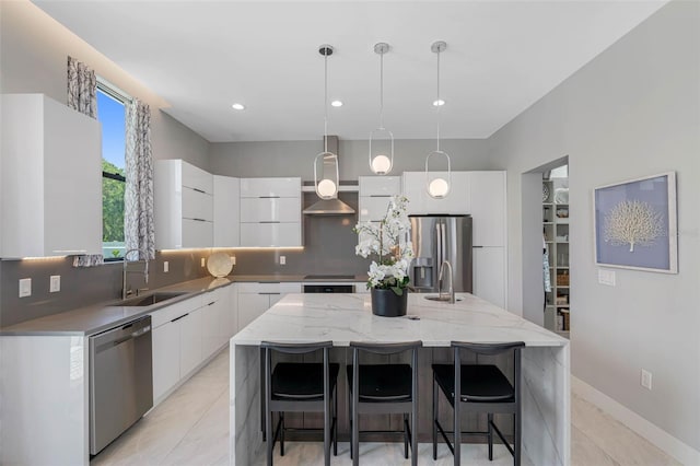 kitchen featuring appliances with stainless steel finishes, white cabinets, modern cabinets, wall chimney exhaust hood, and a sink