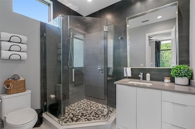 bathroom with vanity, a shower stall, toilet, and visible vents