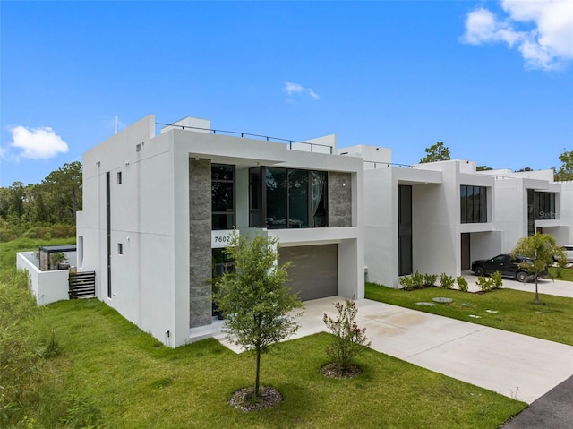 contemporary home featuring stucco siding, concrete driveway, and a front lawn