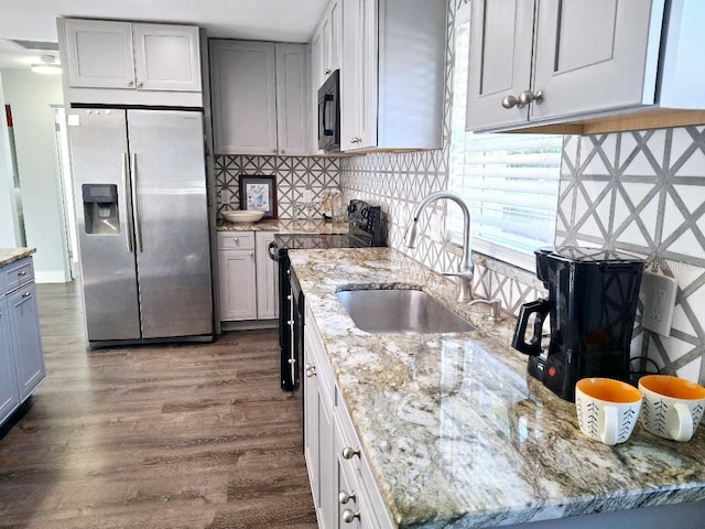 kitchen featuring light stone countertops, gray cabinets, black appliances, and sink