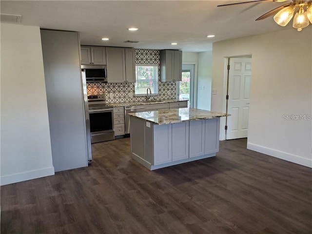 kitchen featuring gray cabinets, appliances with stainless steel finishes, dark hardwood / wood-style floors, a kitchen island, and sink