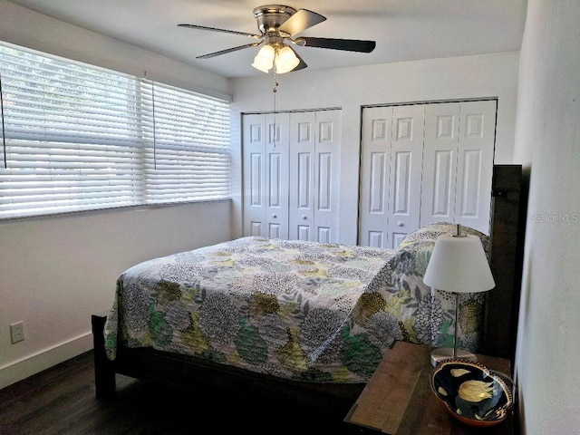 bedroom with dark wood-type flooring, two closets, and ceiling fan