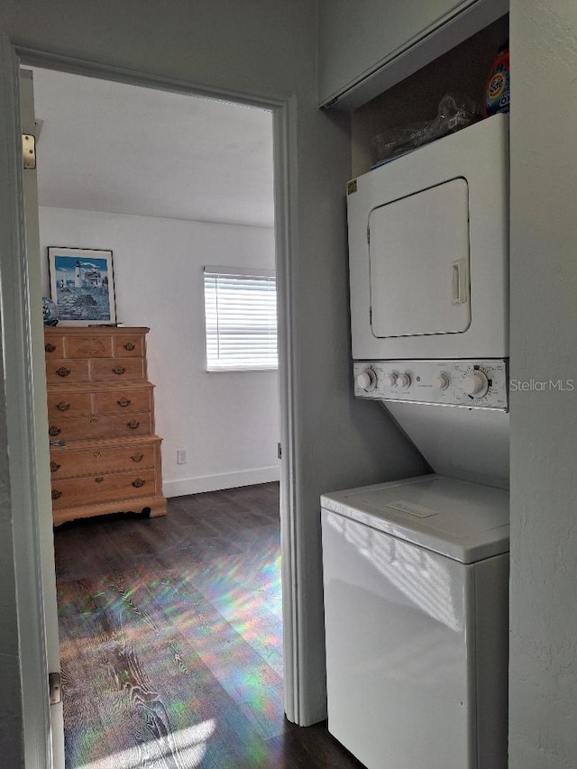 laundry room with dark wood-type flooring and stacked washer / dryer