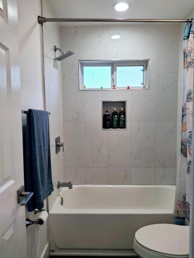 bathroom featuring toilet and shower / bath combination with curtain