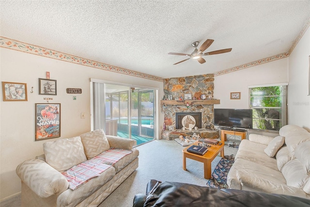 living room featuring carpet flooring, ceiling fan, a fireplace, and a textured ceiling