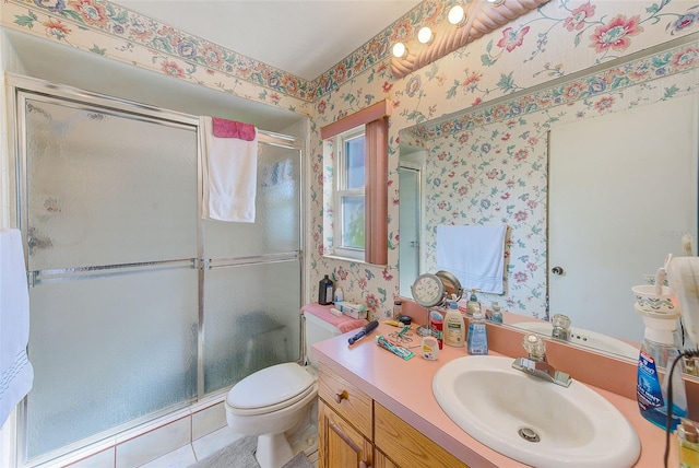 bathroom featuring tile patterned flooring, vanity, toilet, and a shower with door