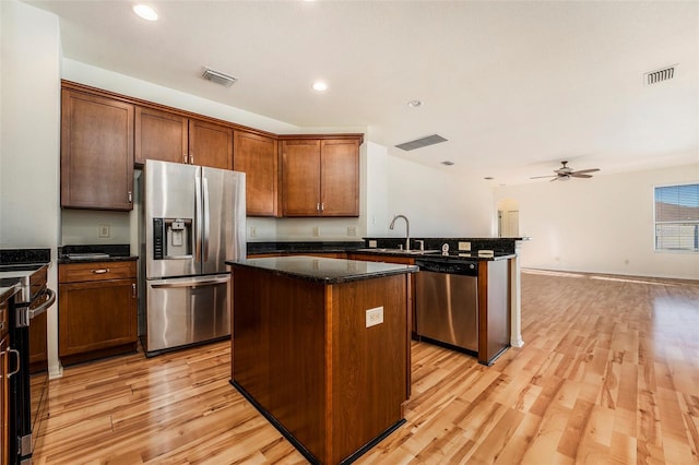 kitchen featuring appliances with stainless steel finishes, light hardwood / wood-style flooring, a kitchen island, and ceiling fan